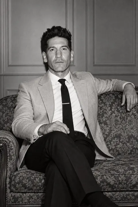 Jon Bernthal — monochrome seated portrait on a vintage sofa, AI-generated