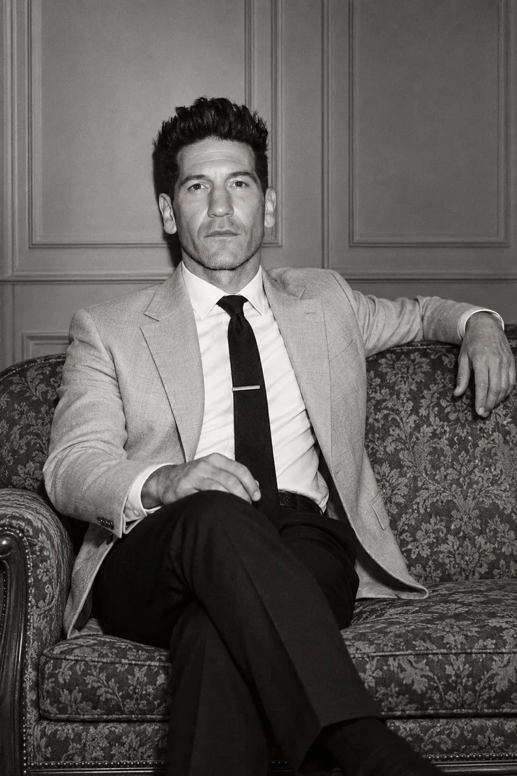 Jon Bernthal — monochrome seated portrait on a vintage sofa, AI-generated